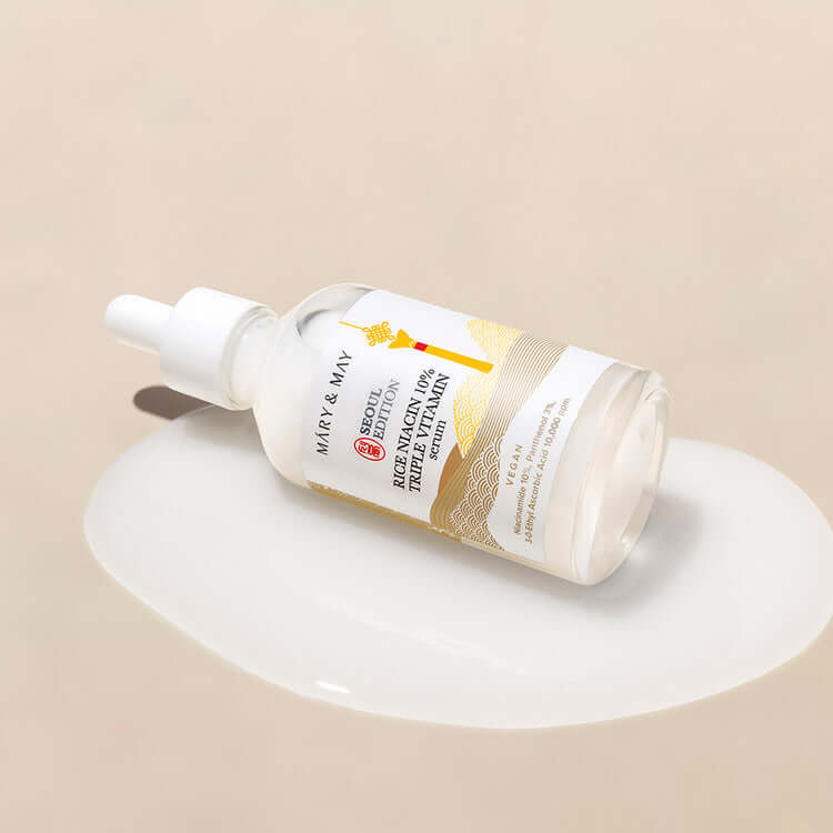 MARY & MAY Rice Niacin 10% triple Vitamin Serum bottle on a beige background