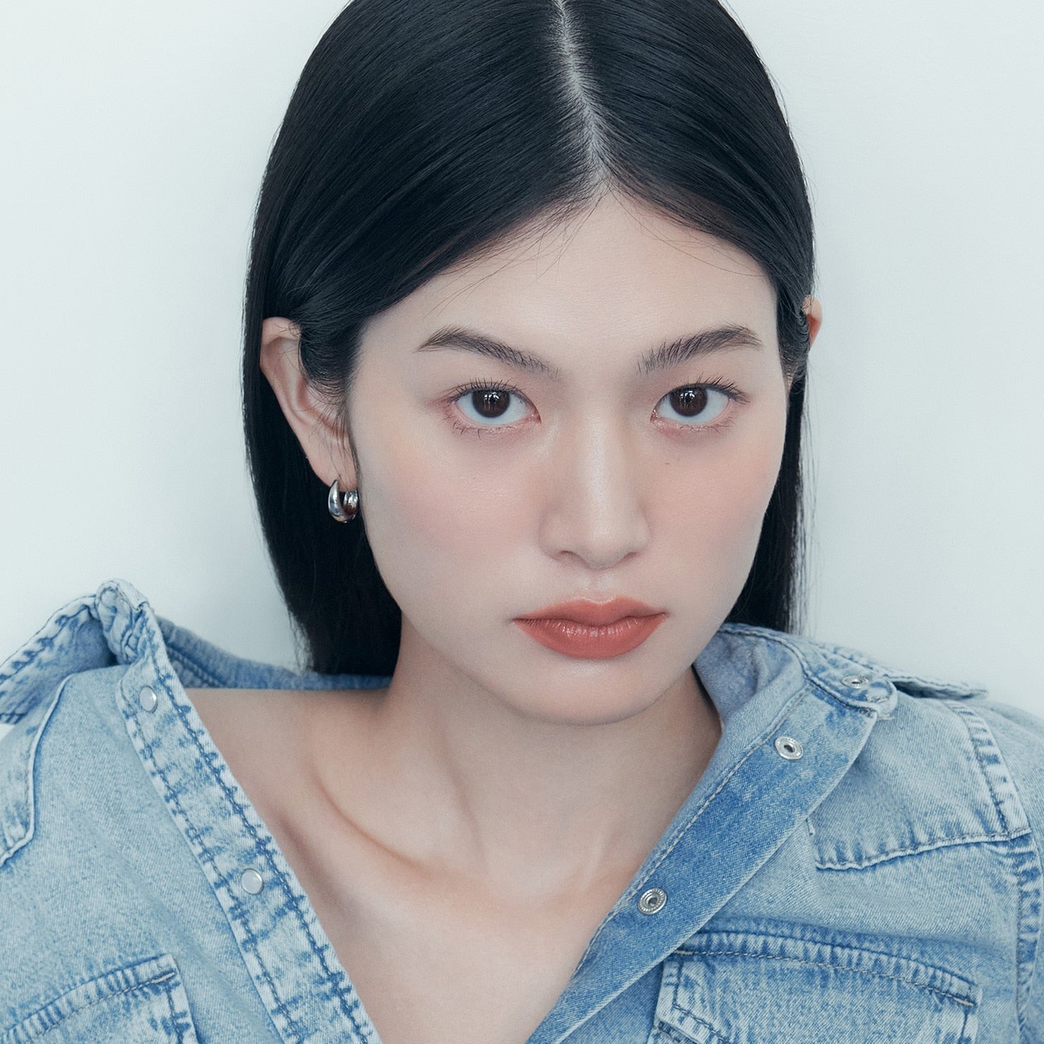 A person with long black hair wearing a denim jacket.