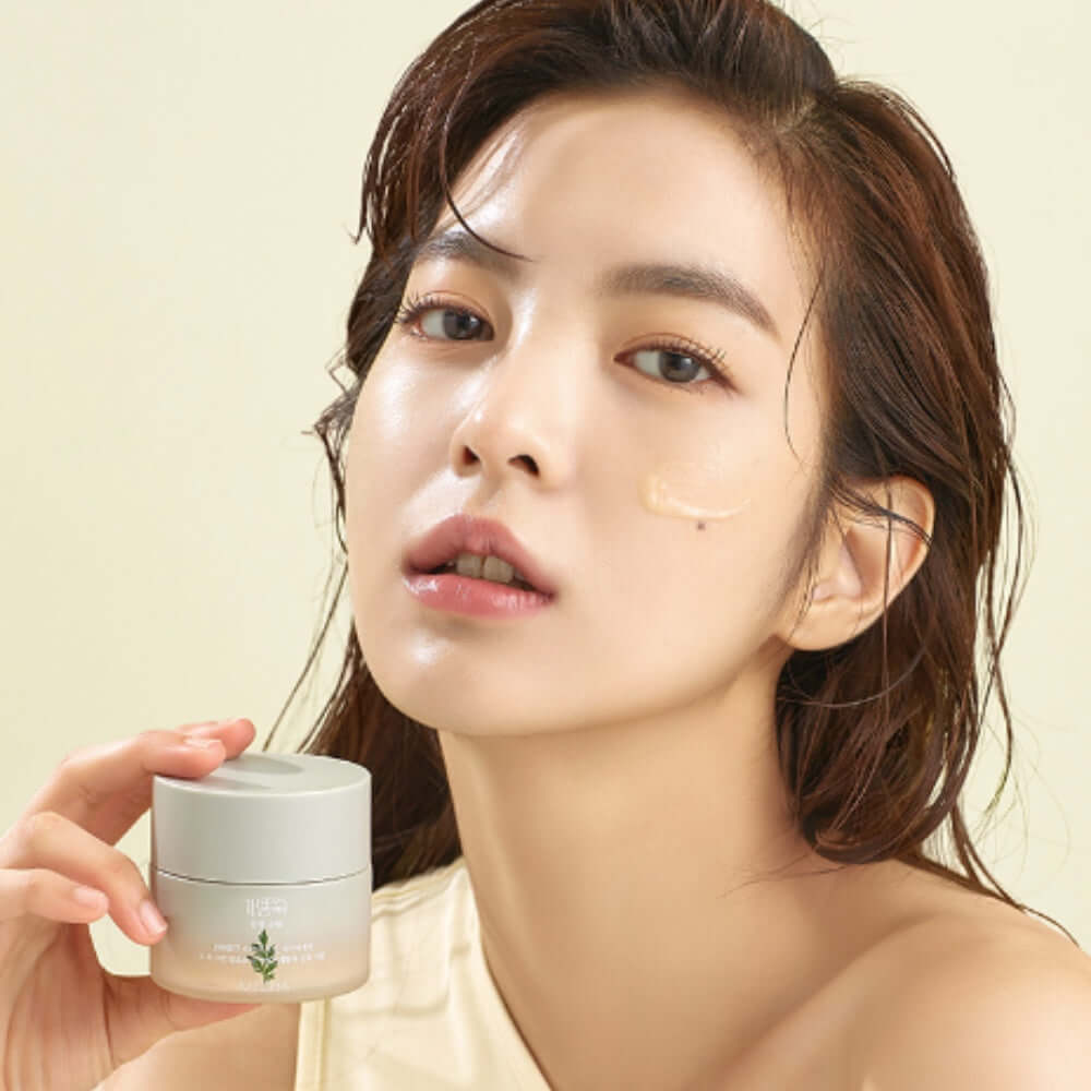 Model applying MISSHA Artemisia soothing cream 50ml on face, featuring product jar held in hand, highlighting skincare benefits.