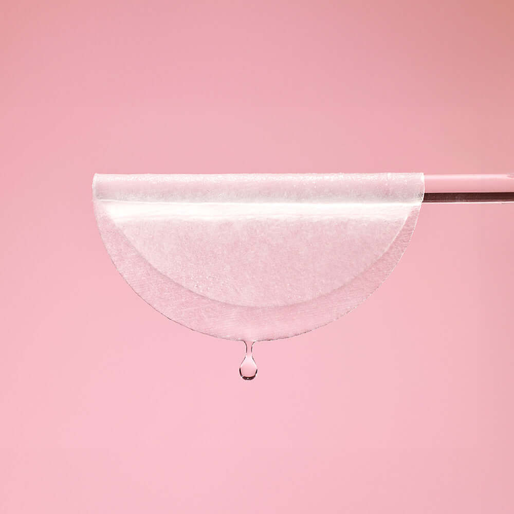 Close-up of MIXSOON Collagen Toner Pad with drop against a pink background, highlighting its hydrating properties.