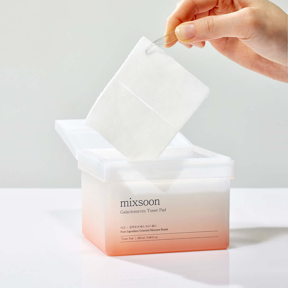 MIXSOON Galactomyces Toner Pad in use, showing a pad being removed from the container for skincare application.