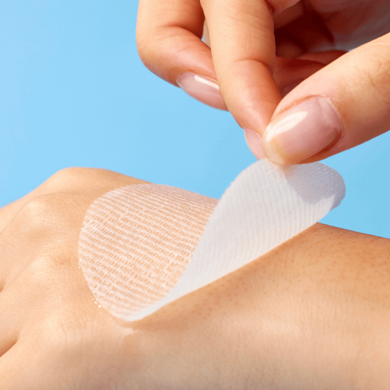 Close-up of a hand holding a MIXSOON Hyaluronic Acid Toner Pad being applied on skin, demonstrating its texture and application.