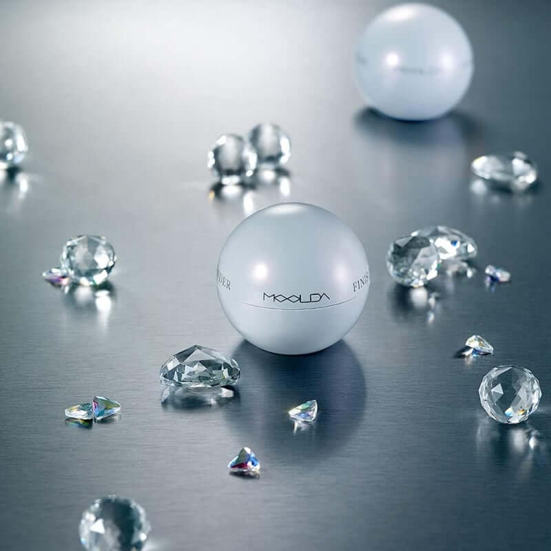 MOOLDA Water Finish Powder on metallic surface with crystal accents, enhancing makeup finish with a luminous touch.