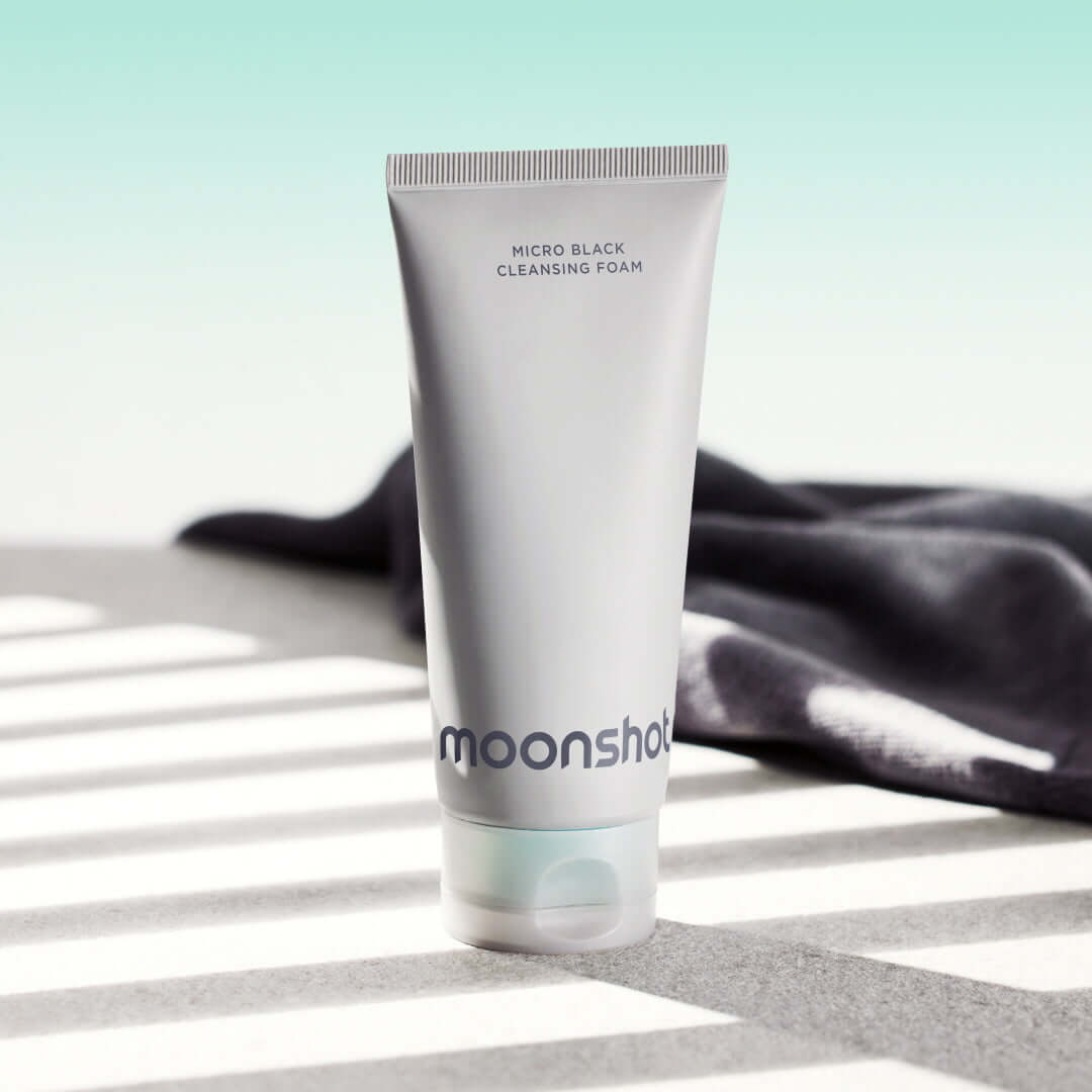 MOONSHOT Micro Black Cleansing Foam tube on a sunny surface with shadows.
