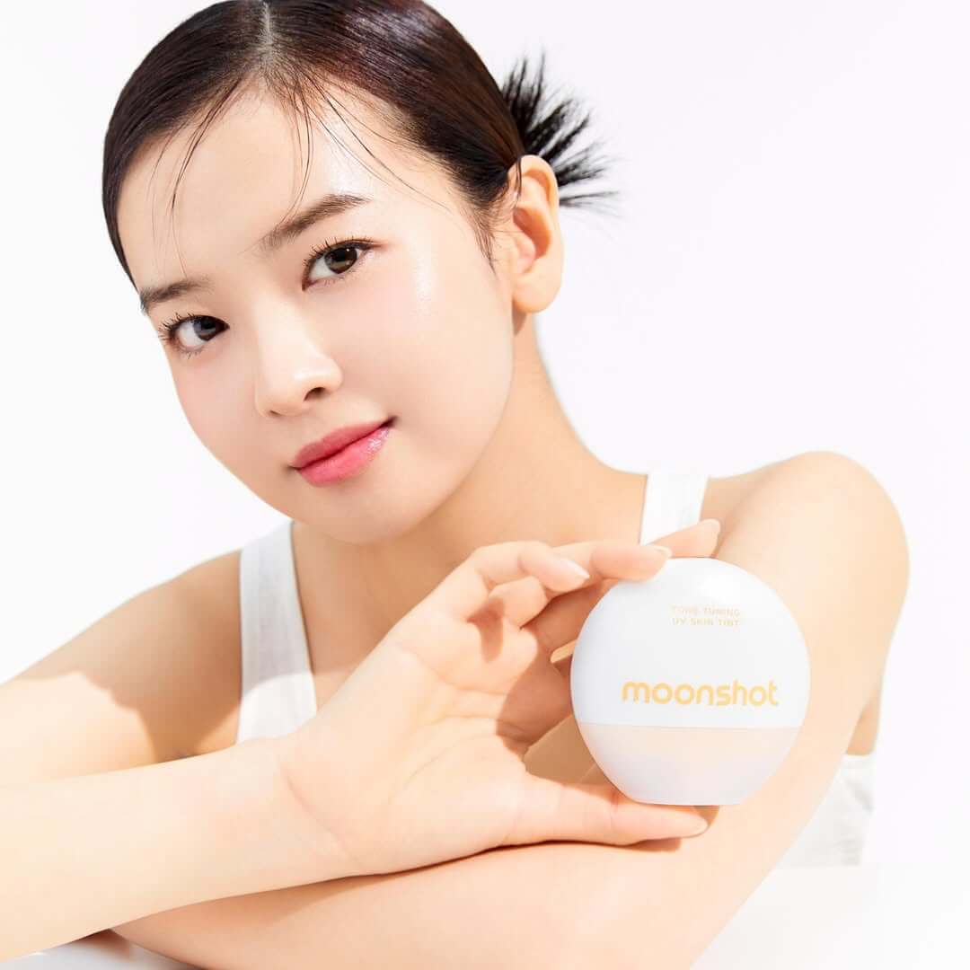 Woman holding MOONSHOT Tone Tuning UV Skin Tint SPF50+ PA++++ bottle