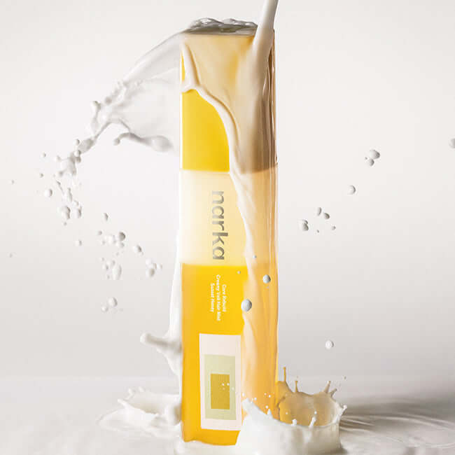 NARKA Creamy Veil Hair Mist bottle with creamy splash background, showcasing product design.