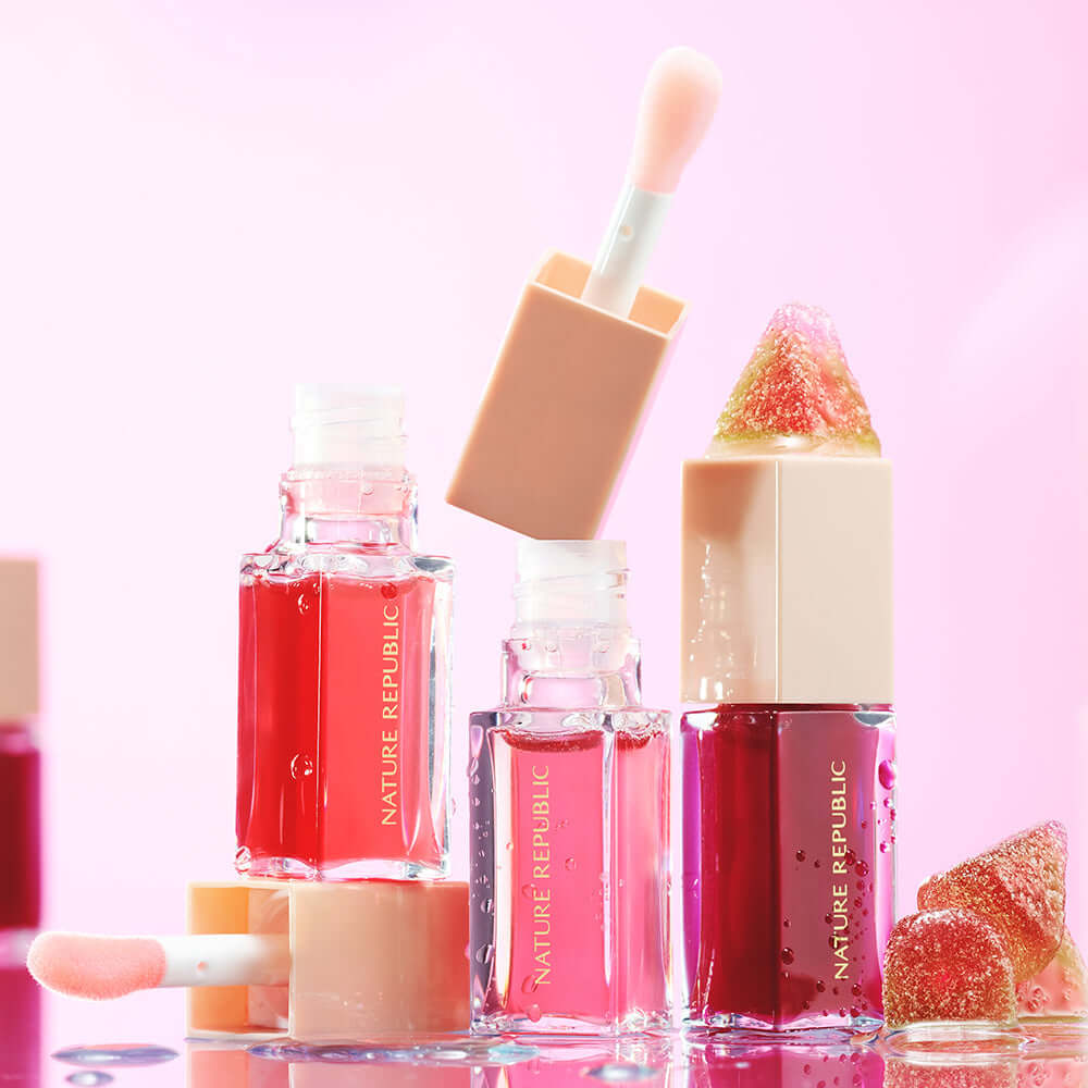NATURE REPUBLIC Glaze Shine Lip Oil in various shades with applicators on pink background.