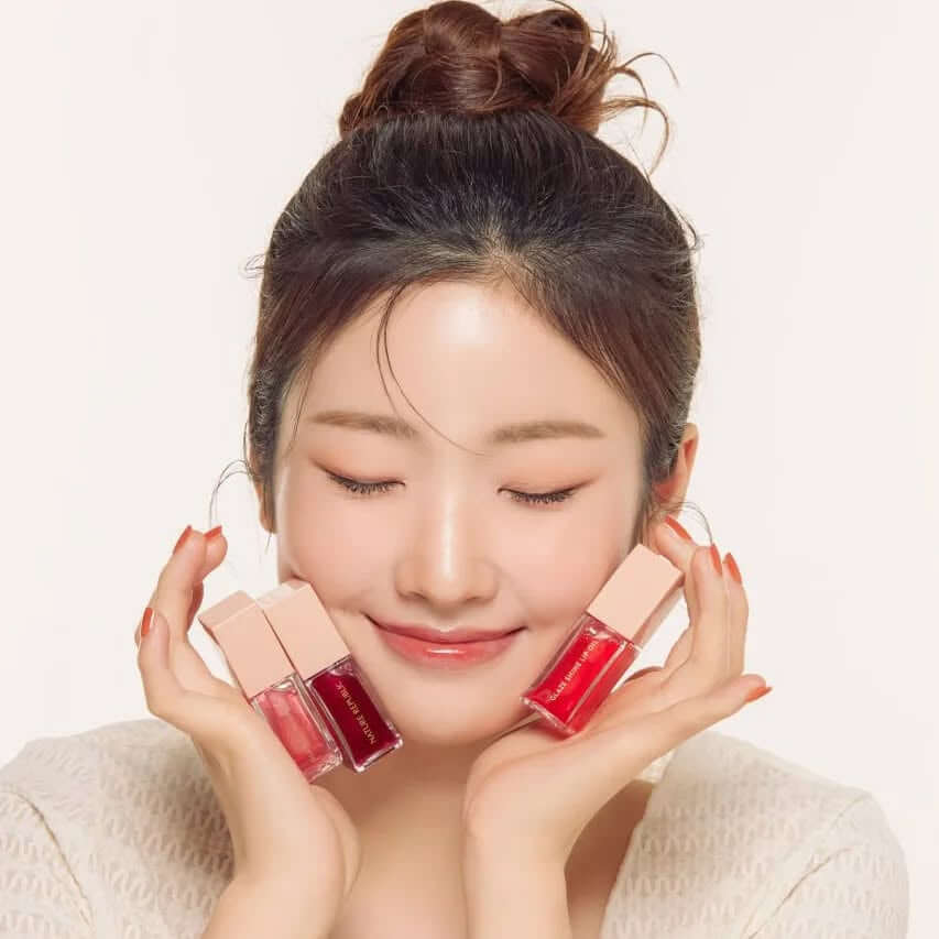 Woman smiling holding NATURE REPUBLIC Glaze Shine Lip Oil bottles
