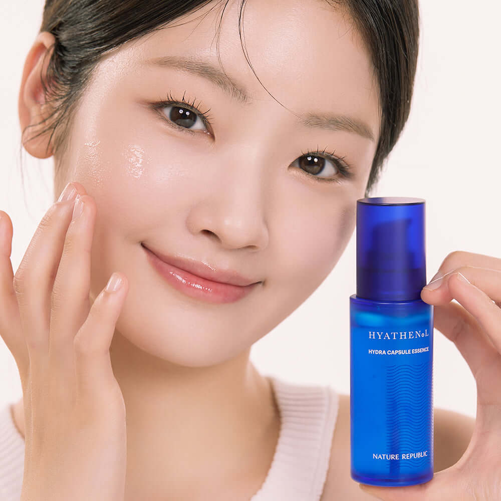 Young woman applying NATURE REPUBLIC Hyathenol Hydra Capsule Essence 50ml for glowing skin.