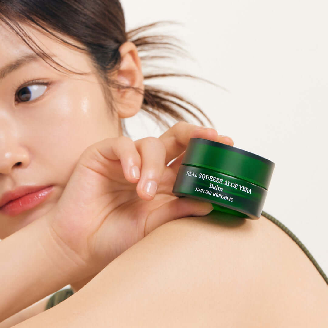 Person holding NATURE REPUBLIC Real Squeeze ALoe Vera Balm 25g jar on shoulder