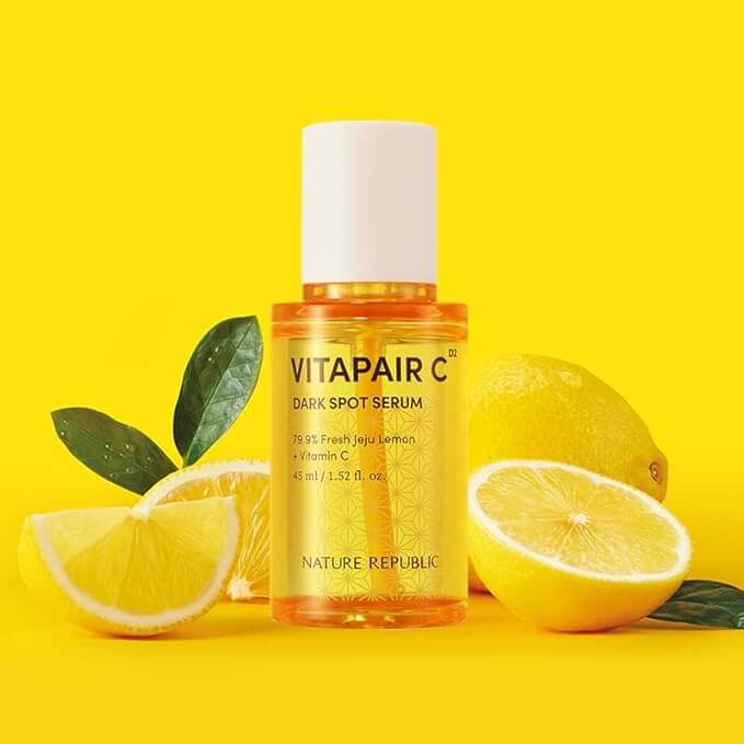 NATURE REPUBLIC Vitapair C SPot Serum 45ml bottle with fresh lemons and green leaves on a vibrant yellow background.