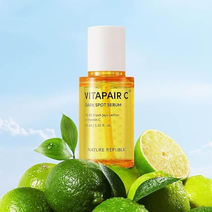 NATURE REPUBLIC Vitapair C SPot Serum 45ml bottle surrounded by fresh green limes, highlighting its natural ingredients.