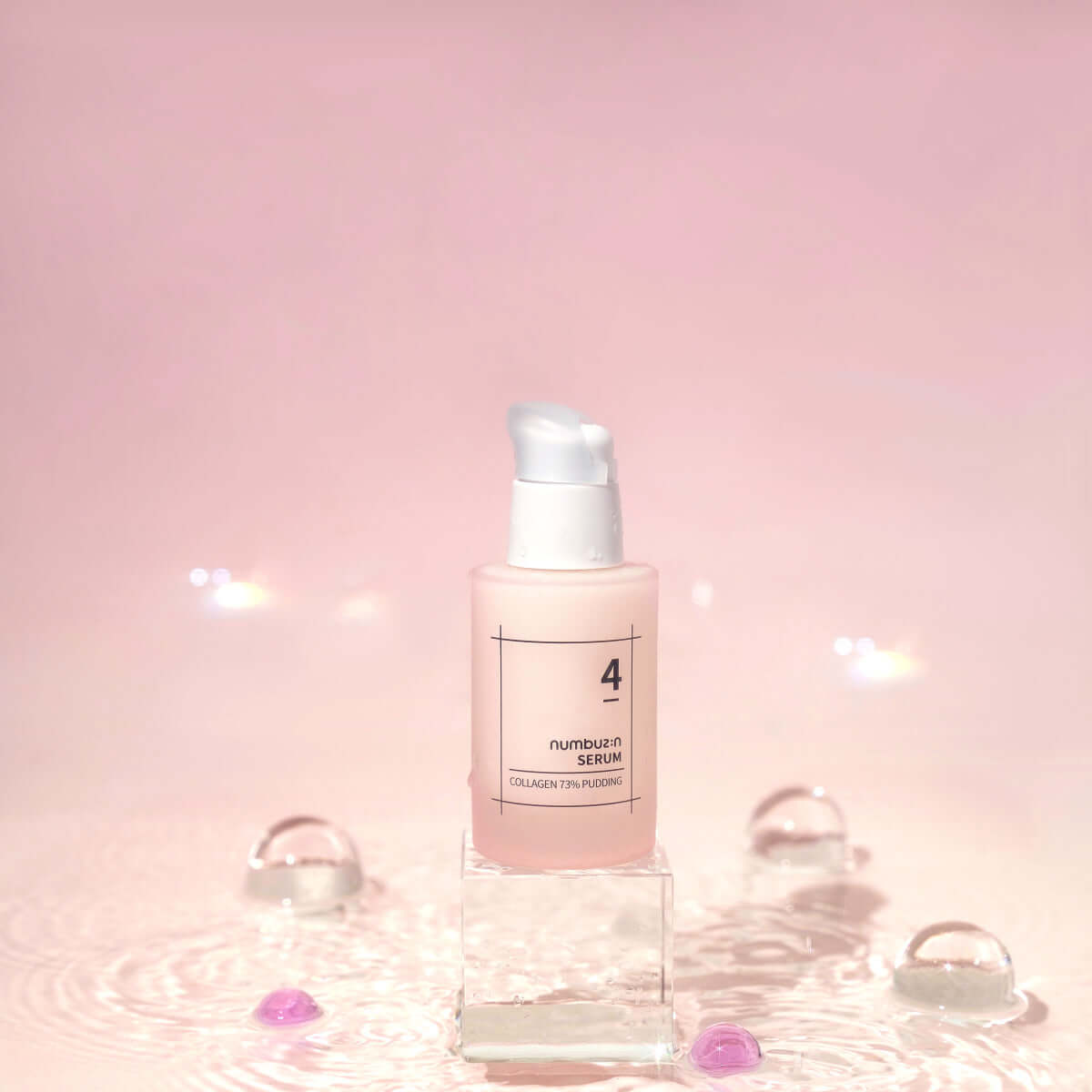 NUMBUZIN No.4 Collagen 73% Pudding Serum bottle on a pink background with droplets.