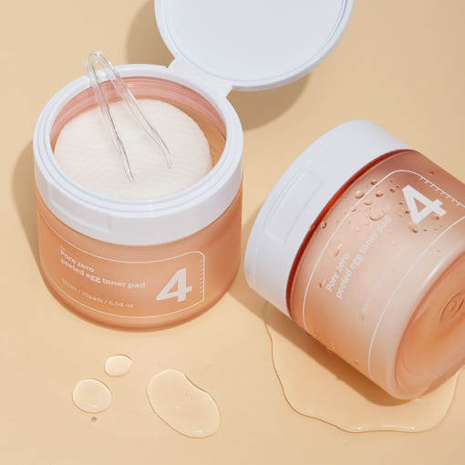 NUMBUZIN No.4 Pore Zero Peeled Egg Toner Pad jars with clear scoop and moisture droplets.