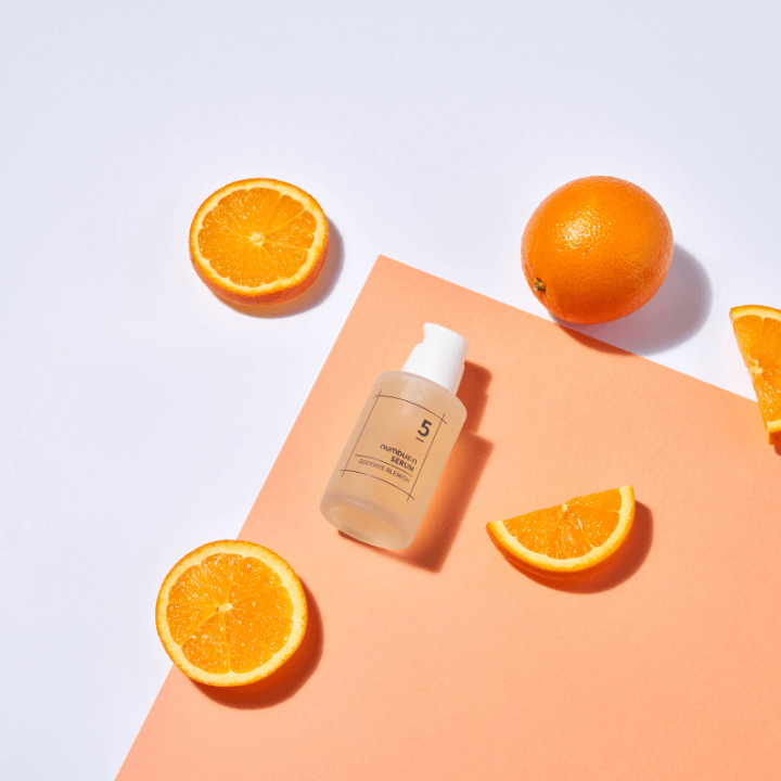 NUMBUZIN No.5 Goodbye Blemish Serum with fresh orange slices on a peach background.