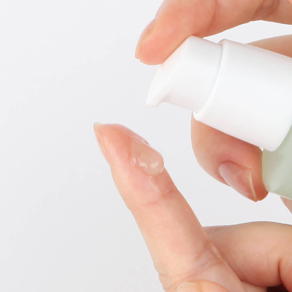 Close-up of NUMBUZIN No.7 Mild Green Soothing Serum being applied, showcasing texture and application process.