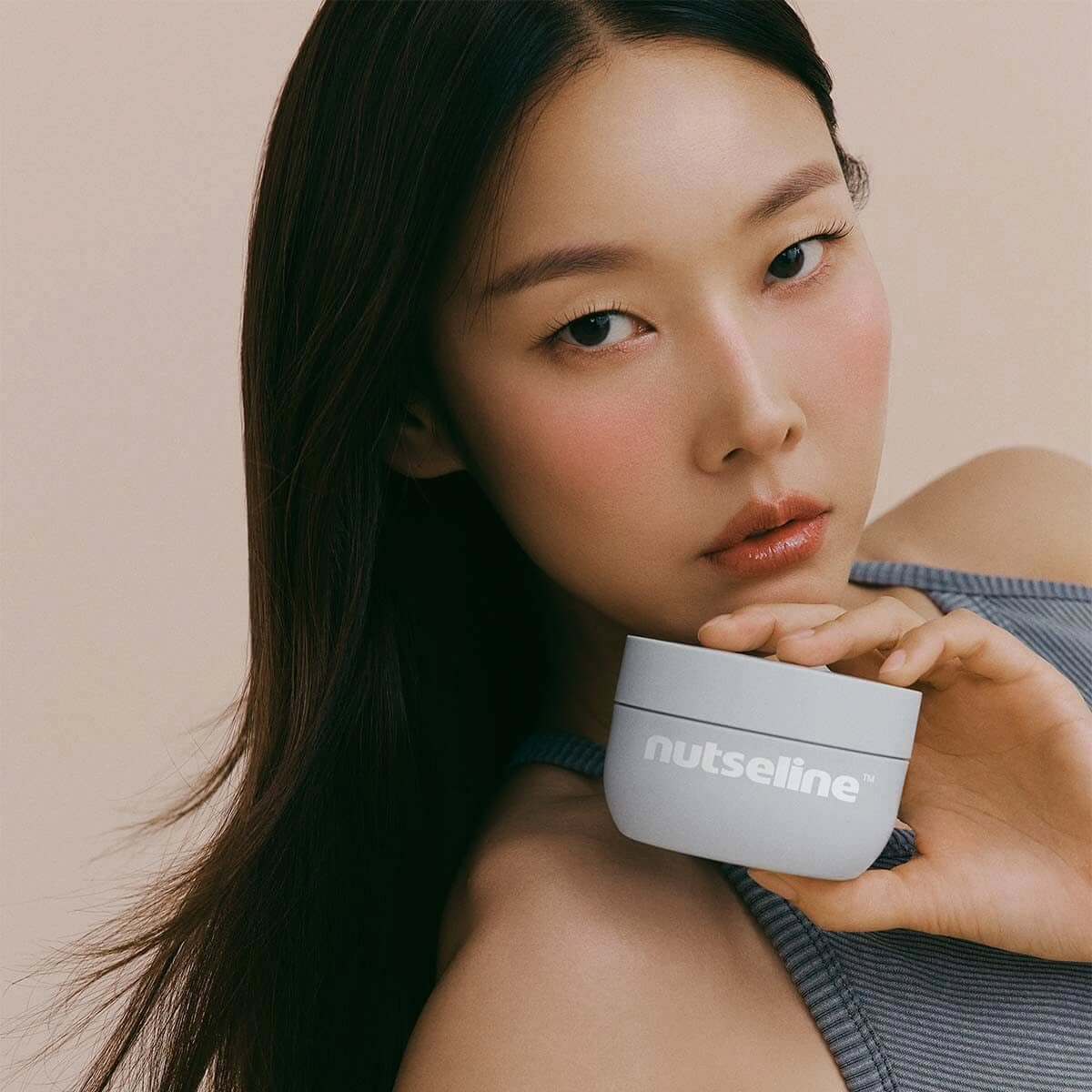 Woman holding NUTSELINE Aroma Nut Gray Body Scrub 200g container