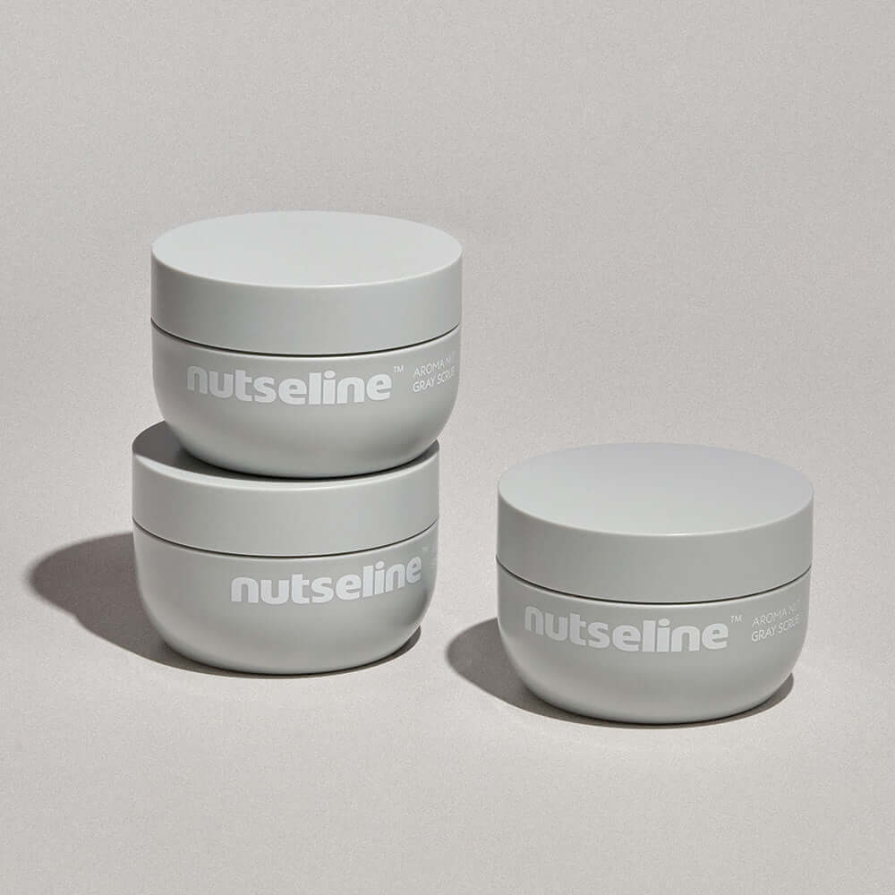 Three jars of NUTSELINE Aroma Nut Gray Body Scrub 200g stacked and displayed on a neutral background