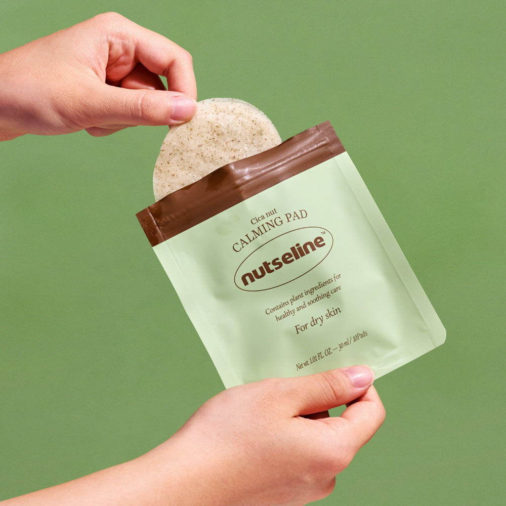 Hands holding NUTSELINE Cica Nut Calming Pads against green background