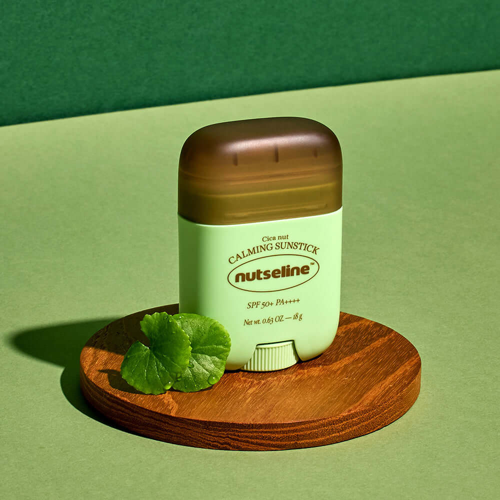 NUTSELINE Cica Nut Calming Sun Stick 18g on wooden platform with leaves, SPF 50+, PA+++ label visible