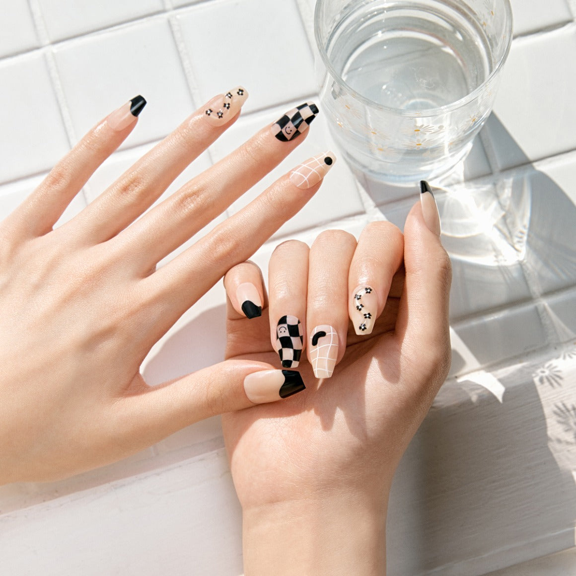 Elegant manicure using DASHING DIVA MAGIC PRESS Nice Way - Coffin nails featuring black and white designs on a tiled surface.