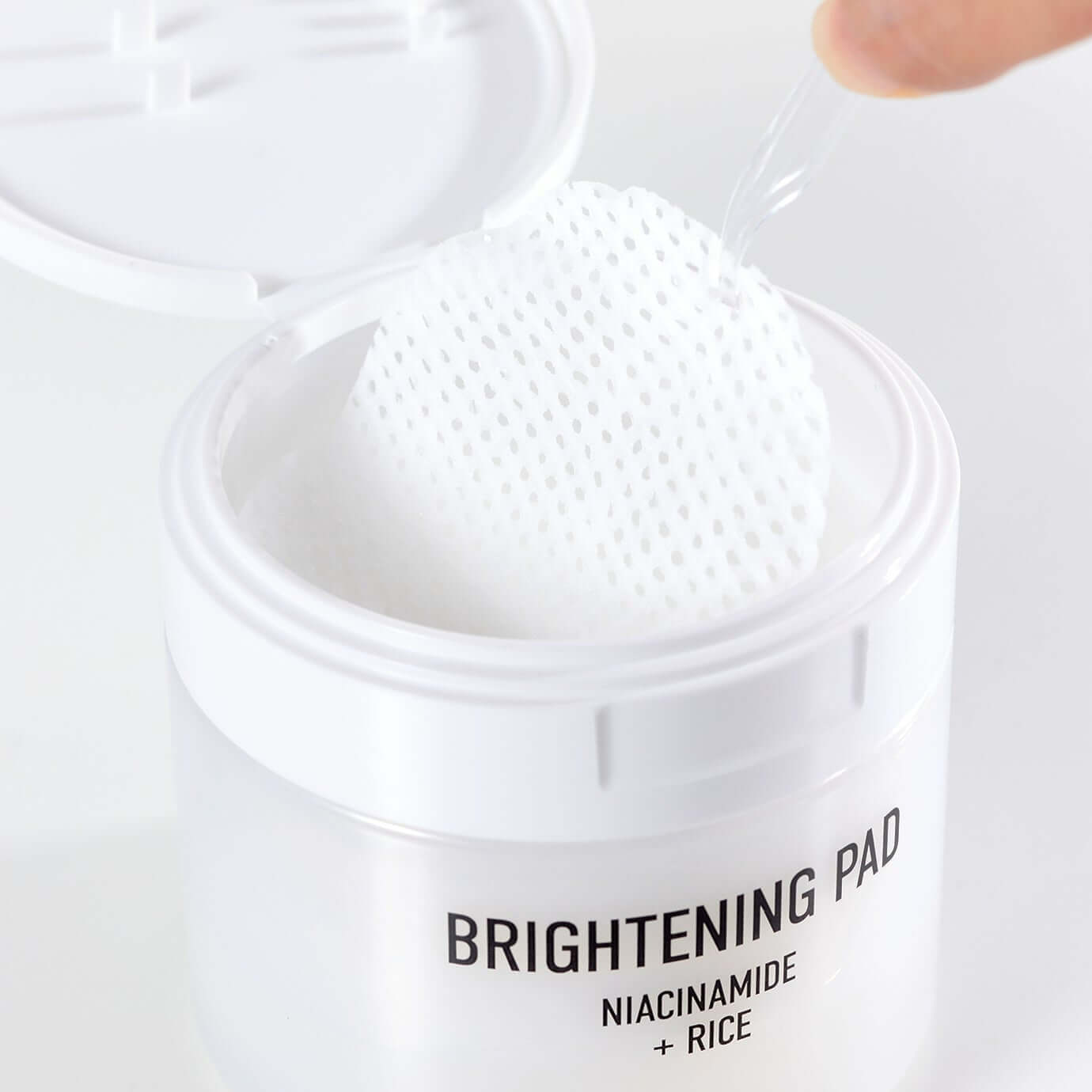 Open container of PARNELL Niacinamide Rice Brightening 60 pads with close-up of textured pad and packaging details.