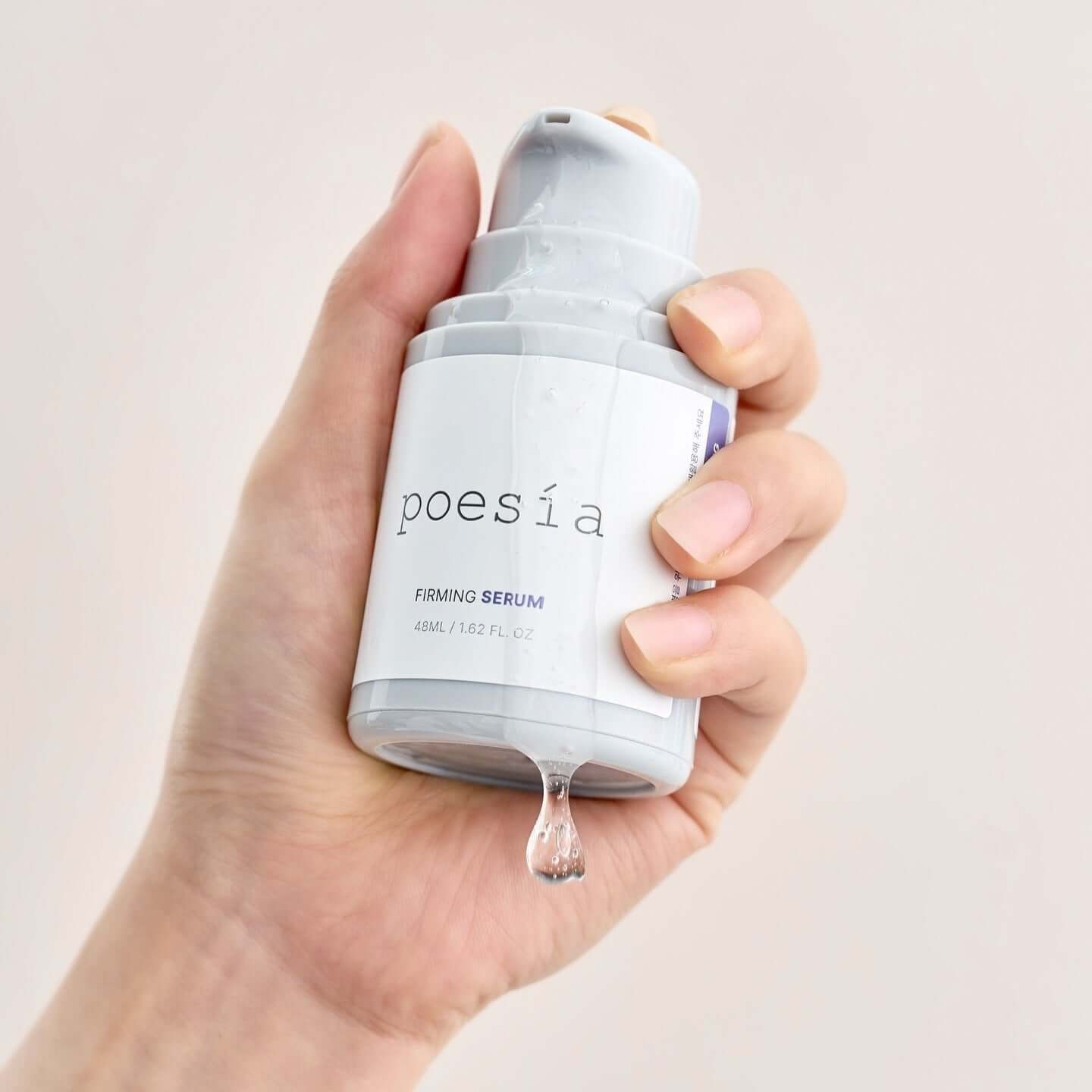 Hand holding POESÃA Hydro Phyto Collagen Deep Farming Ampoule Serum 48ml bottle with drop of serum.