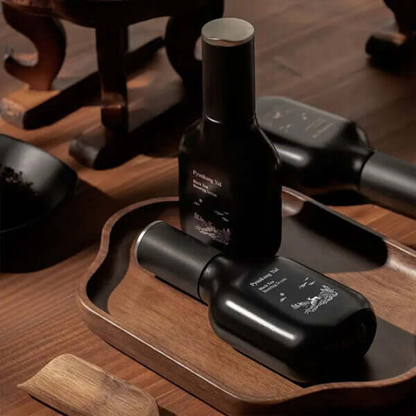 PYUNKANG YUL Black Tea Boosting Serum 45ml on a wooden tray, showcasing premium skincare with elegant packaging.