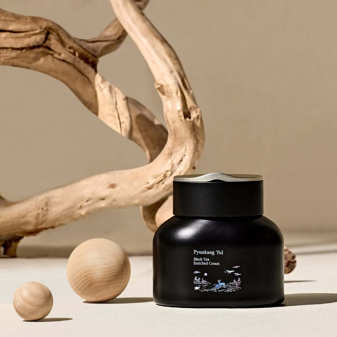 PYUNKANG YUL Black Tea Enriched Cream 60ml in elegant black jar with natural wood accents, luxury skincare product display.