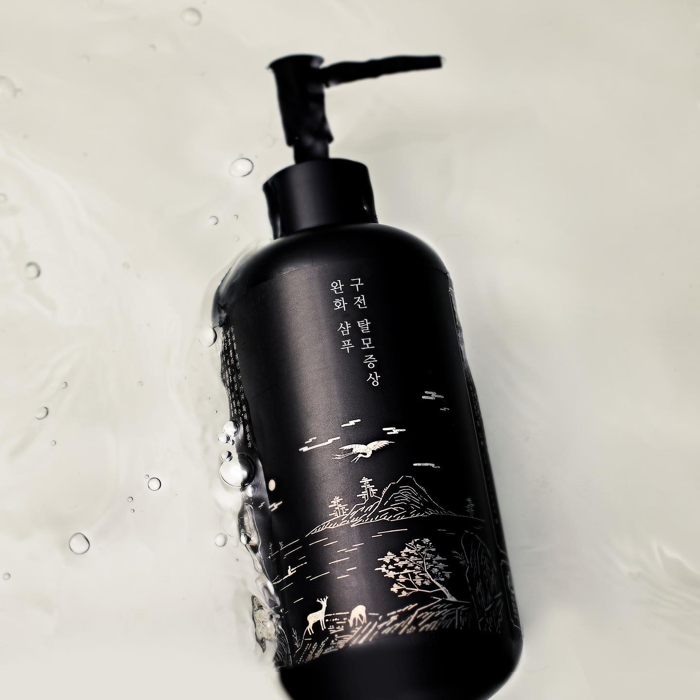 Bottle of PYUNKANG YUL Black Tea Oral Hair Loos Relief Shampoo 500ml floating in water.