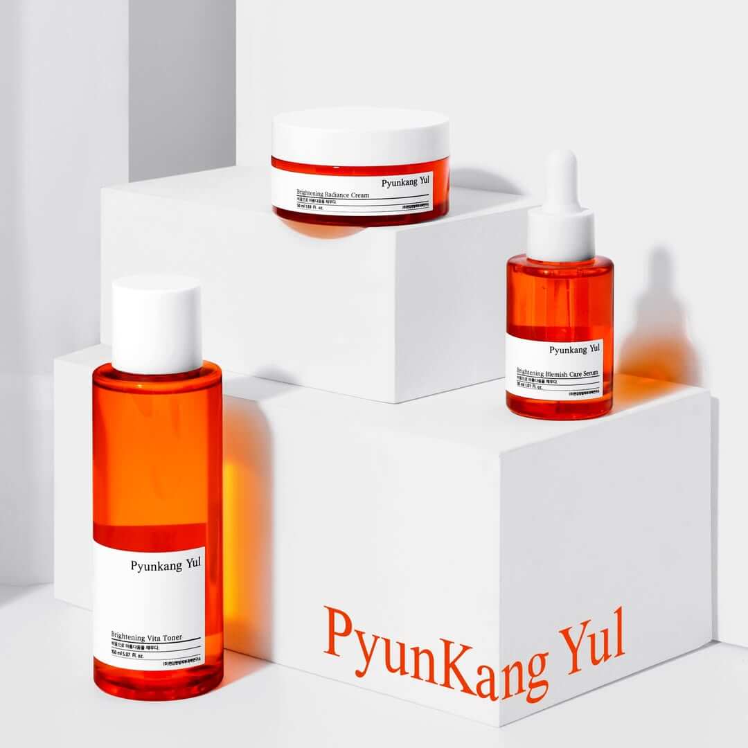 PYUNKANG YUL Brightening Bojagi Gift Set displayed on white blocks with toner, cream, and serum bottles.