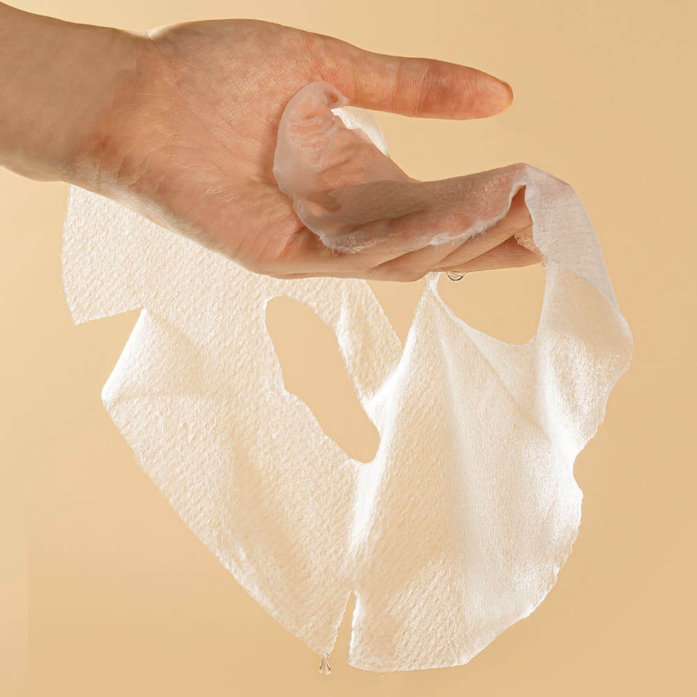 Hand holding a PYUNKANG YUL Brightening Porcelain Skin Mask from the 10 pieces pack, showcasing texture and quality.