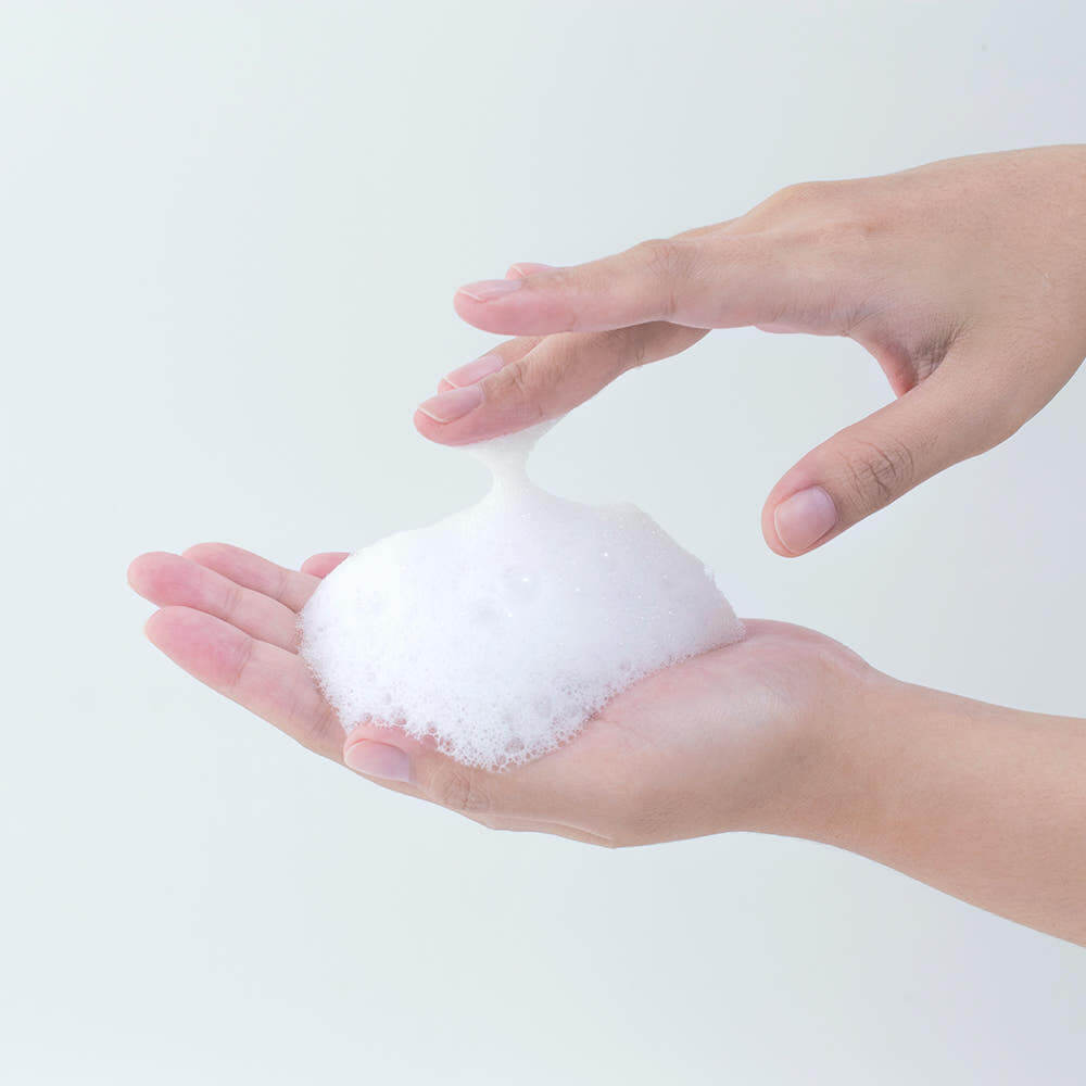 Hands holding foam from PYUNKANG YUL Calming Acne Clear Body Wash 290ml, demonstrating its rich lather and cleansing properties.