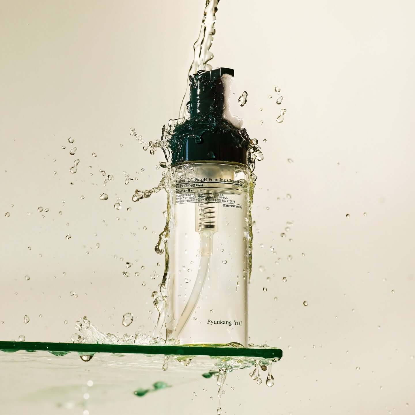 PYUNKANG YUL Calming Low pH Foaming Cleanser 150ml bottle with splashing water, showcasing refreshing skincare product.