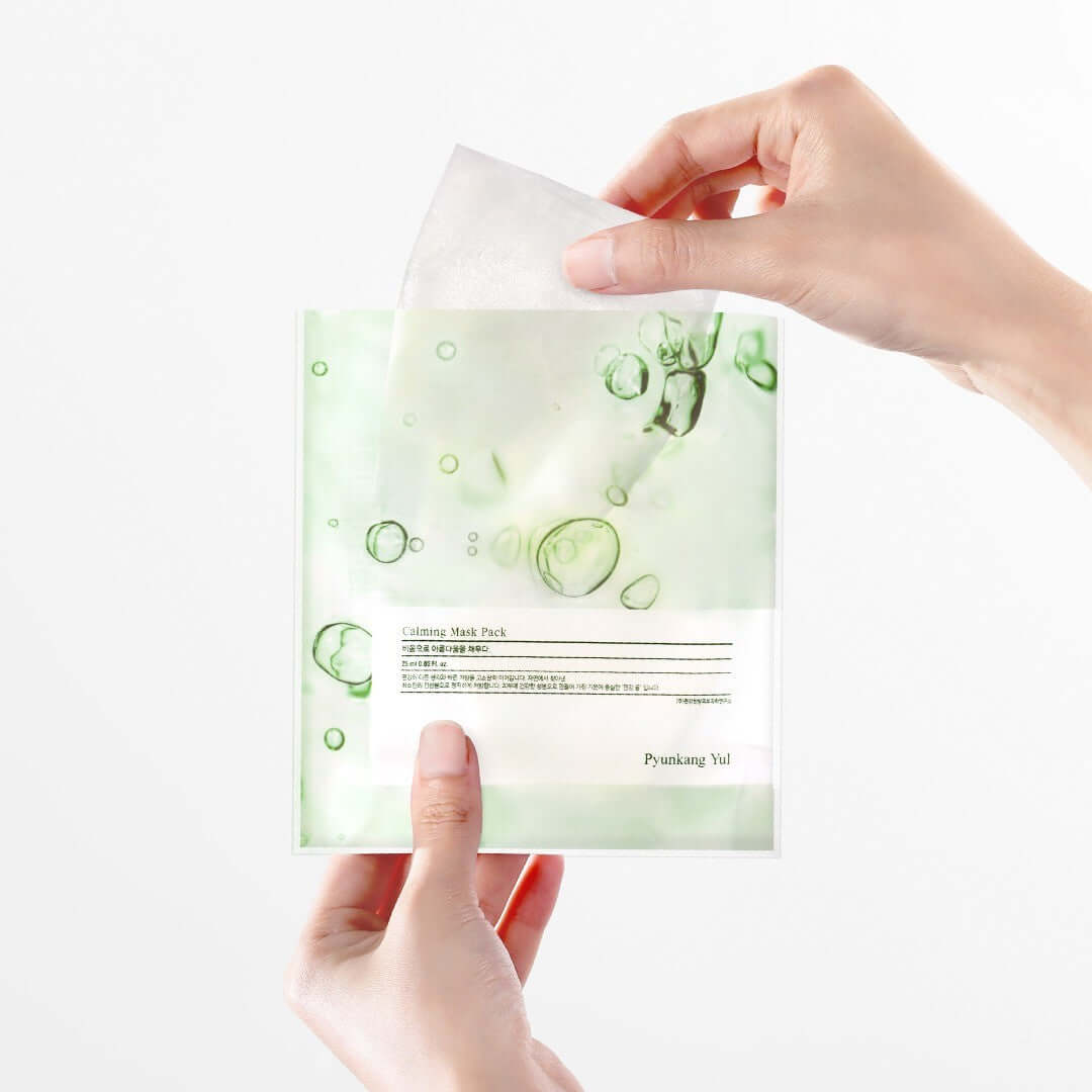 Hands holding a sheet from PYUNKANG YUL Calming Mask Pack 10 Pieces.