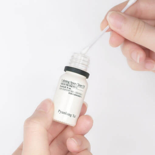 Person applying PYUNKANG YUL Calming Spot Clear Oil 10ml with a cotton swab