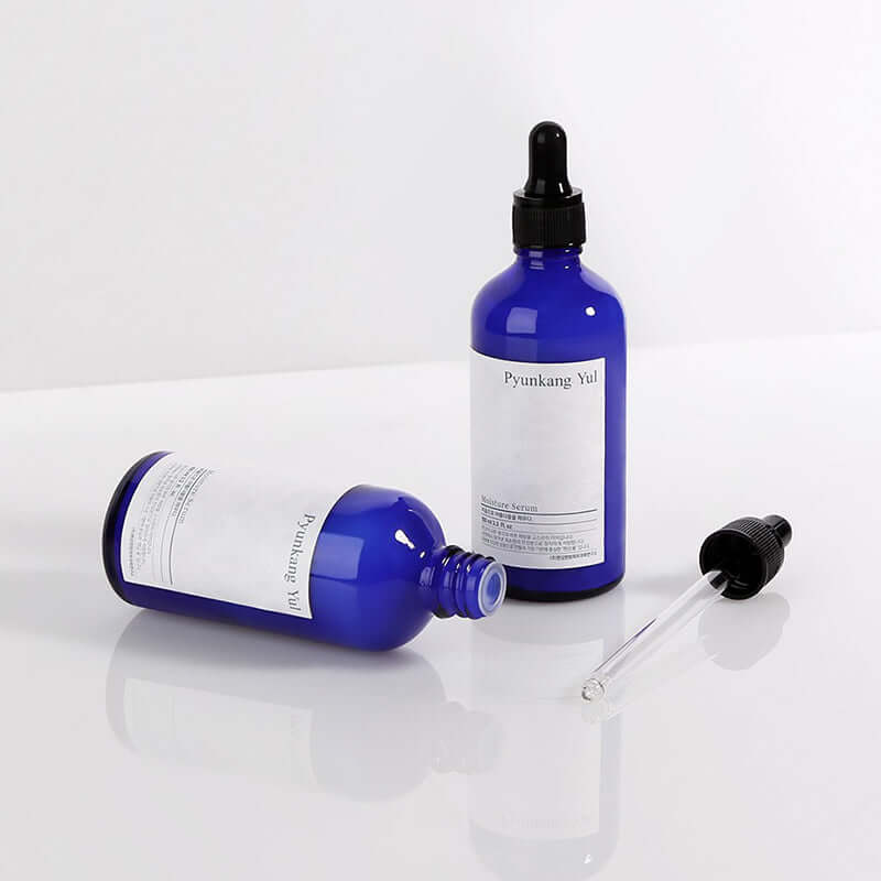 Blue bottles of PYUNKANG YUL Moisture Serum 100ml with droppers on white background