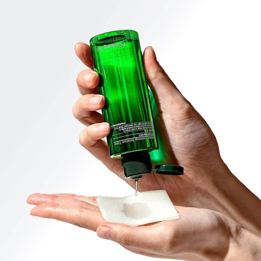 Hands using PYUNKANG YUL Ultimate Soothing Solution Toner 110ml on cotton pad