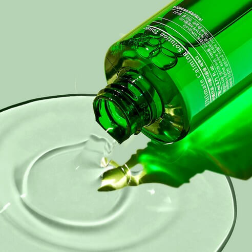 PYUNKANG YUL Ultimate Soothing Solution Toner 110ml bottle pouring liquid on a green surface