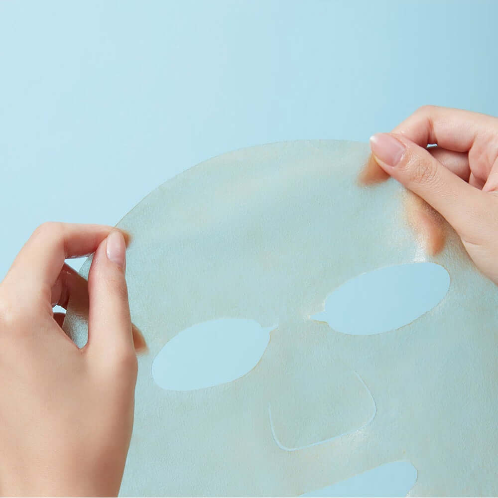 REAL BARRIER Cica Relief Rx Fade-In Serum Mask 10 Sheets being held by hands against a light blue background