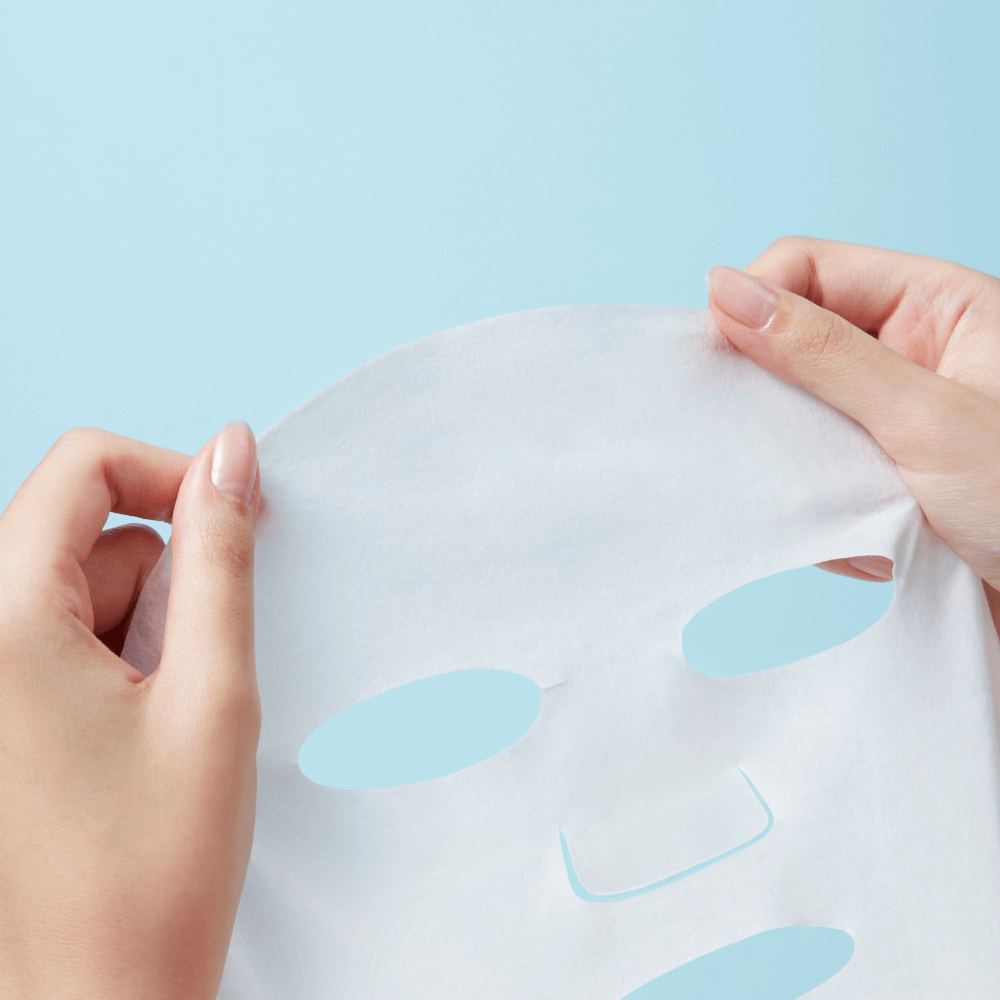 Holding REAL BARRIER Extreme Cream Mask 10 Sheets against light blue background