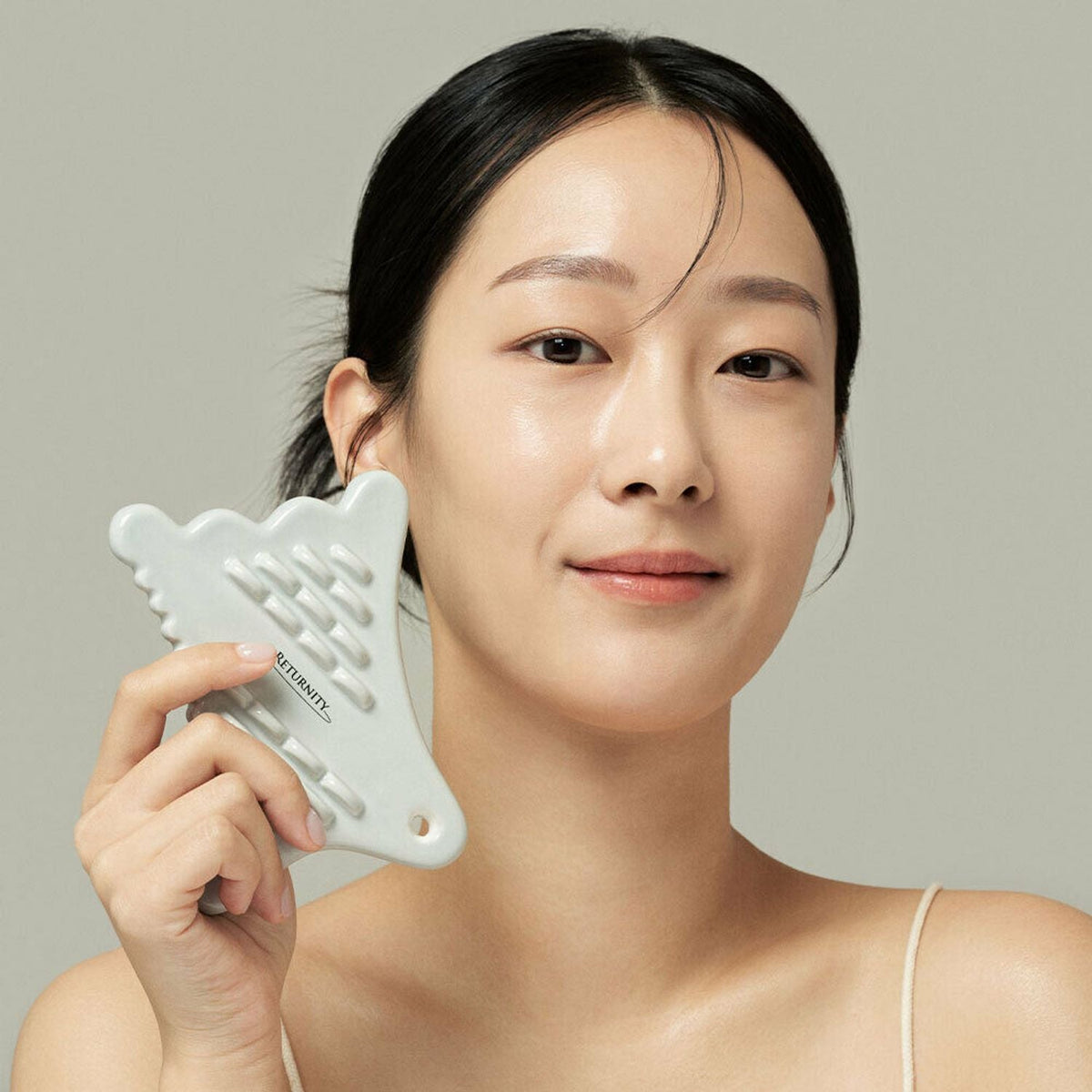 Woman holding RETURNITY Guasha tool.
