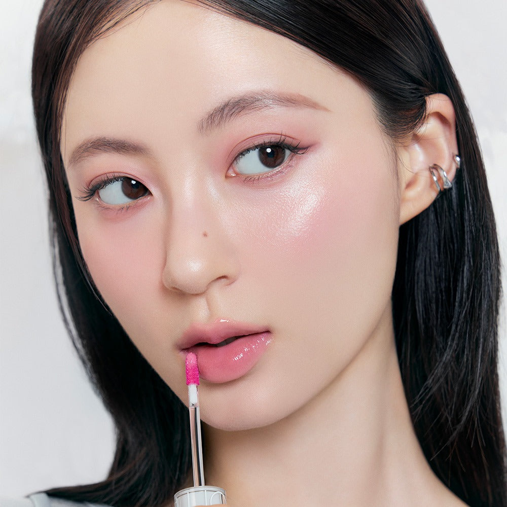 Model applying ROMAND x Joanne Friends The Juicy Lasting Tint for a glossy lip finish.