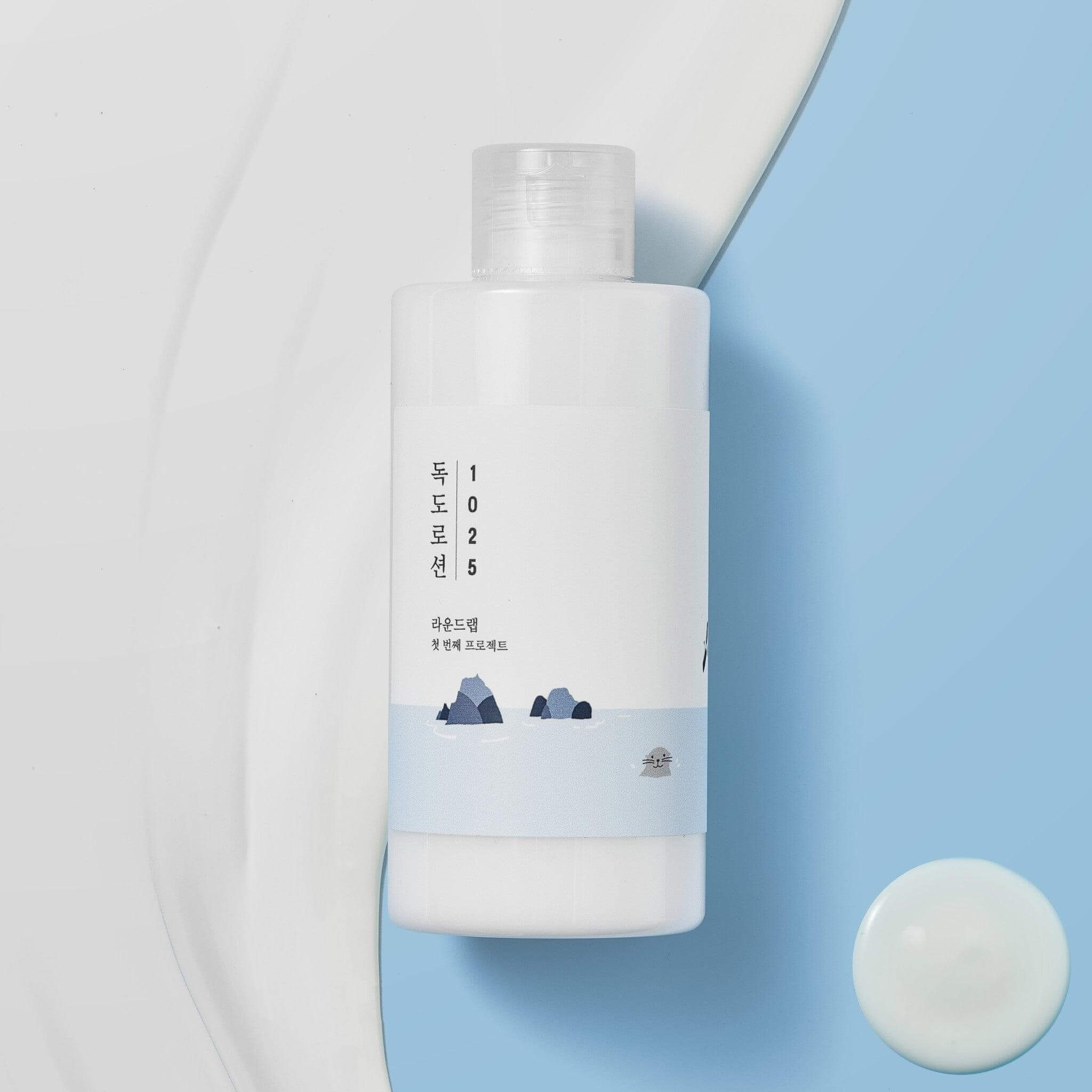 ROUND LAB 1025 Dokdo Lotion 400ml bottle on blue and white background with lotion texture