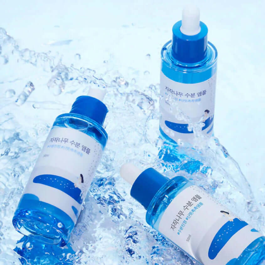 Three bottles of ROUND LAB Birch Moisture Ampoule 50ml on a watery surface