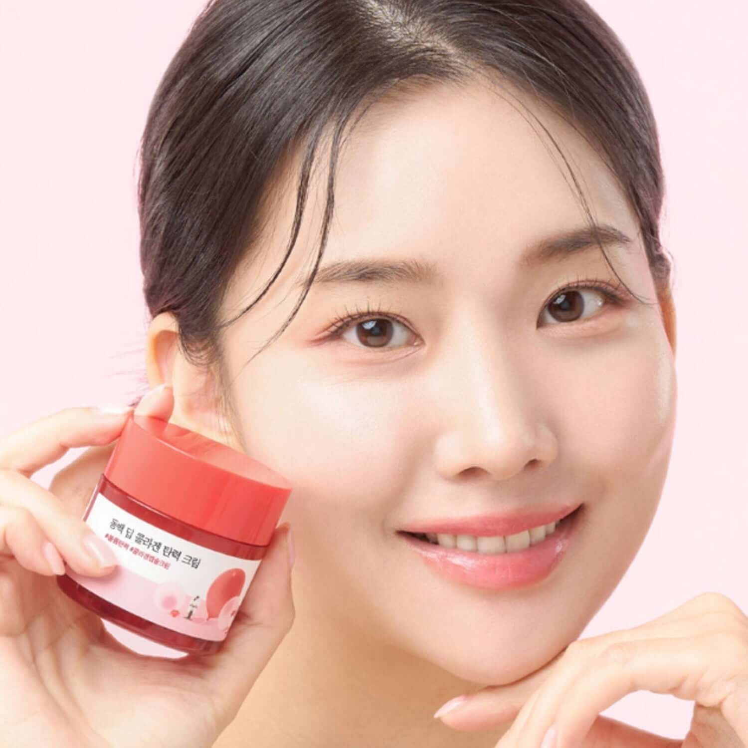 Smiling woman holding ROUND LAB Dongbaek Deep Collagen Elasticity Cream 50ml