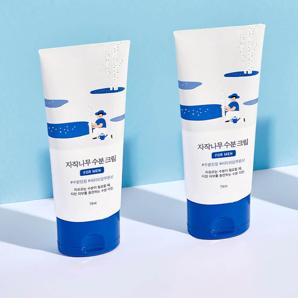 Two tubes of ROUND LAB For Men Birch Moisture Cream 75ml placed against a blue background.