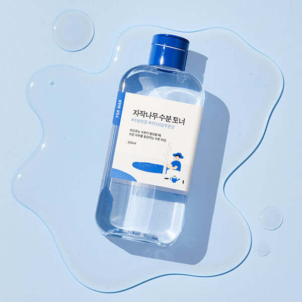 ROUND LAB For Men Birch Moisture Toner 200ml bottle on a blue background with water droplets.