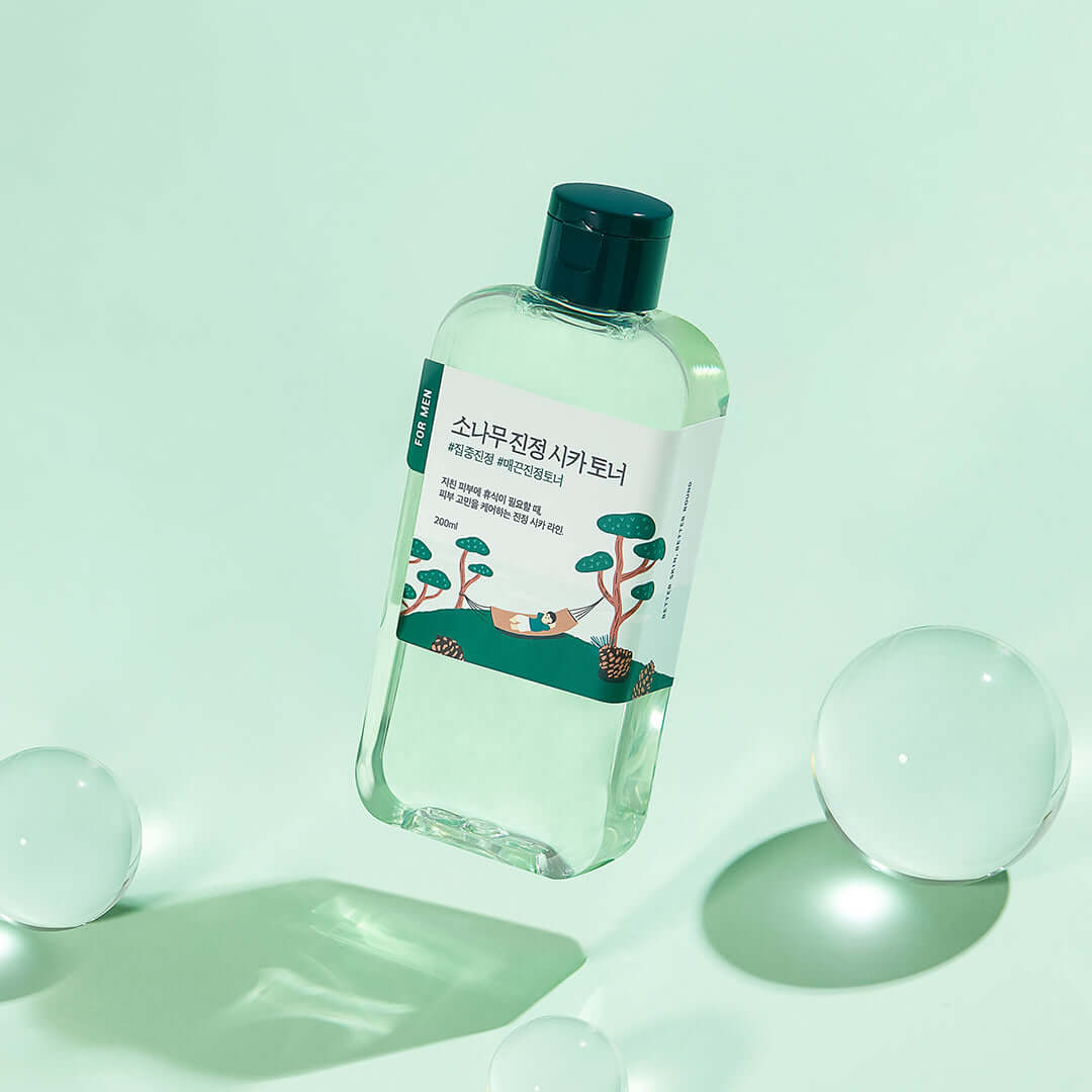 ROUND LAB For Men Pine Calming Cica Toner 200ml bottle on green background with bubbles.