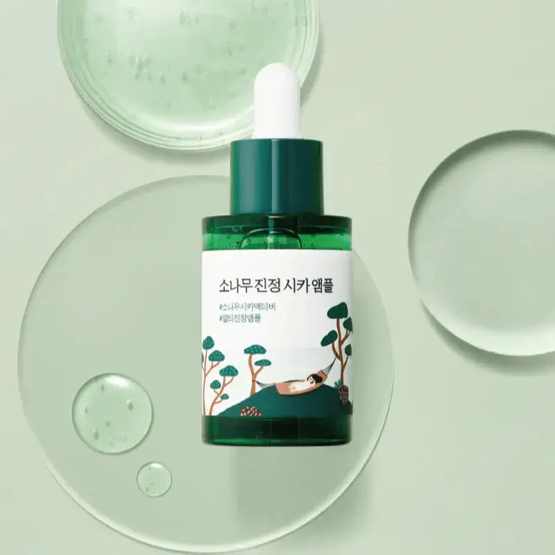 ROUND LAB Pine Calming Cica Ampoule 30ml with green dropper bottle on a light background with liquid droplets.